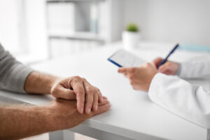 medicine, healthcare and old people concept - close up of senior man and doctor in medical office at hospital