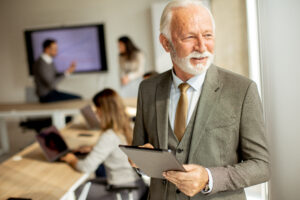 Handsome senior business man working on digital tablet in the office